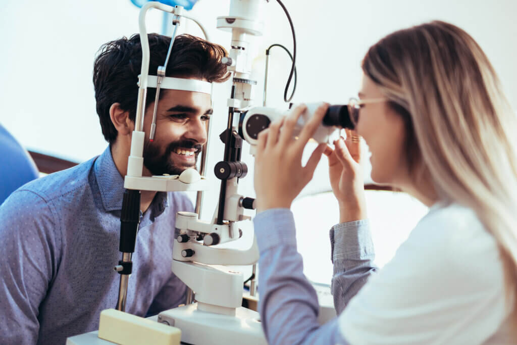 Female optometrist performing an eye exam on a dark-haired male patient