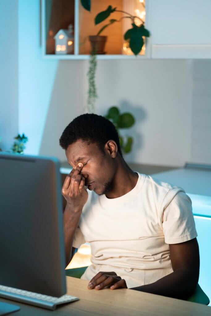 Young man looking at a computer screen and rubbing his strained eyes