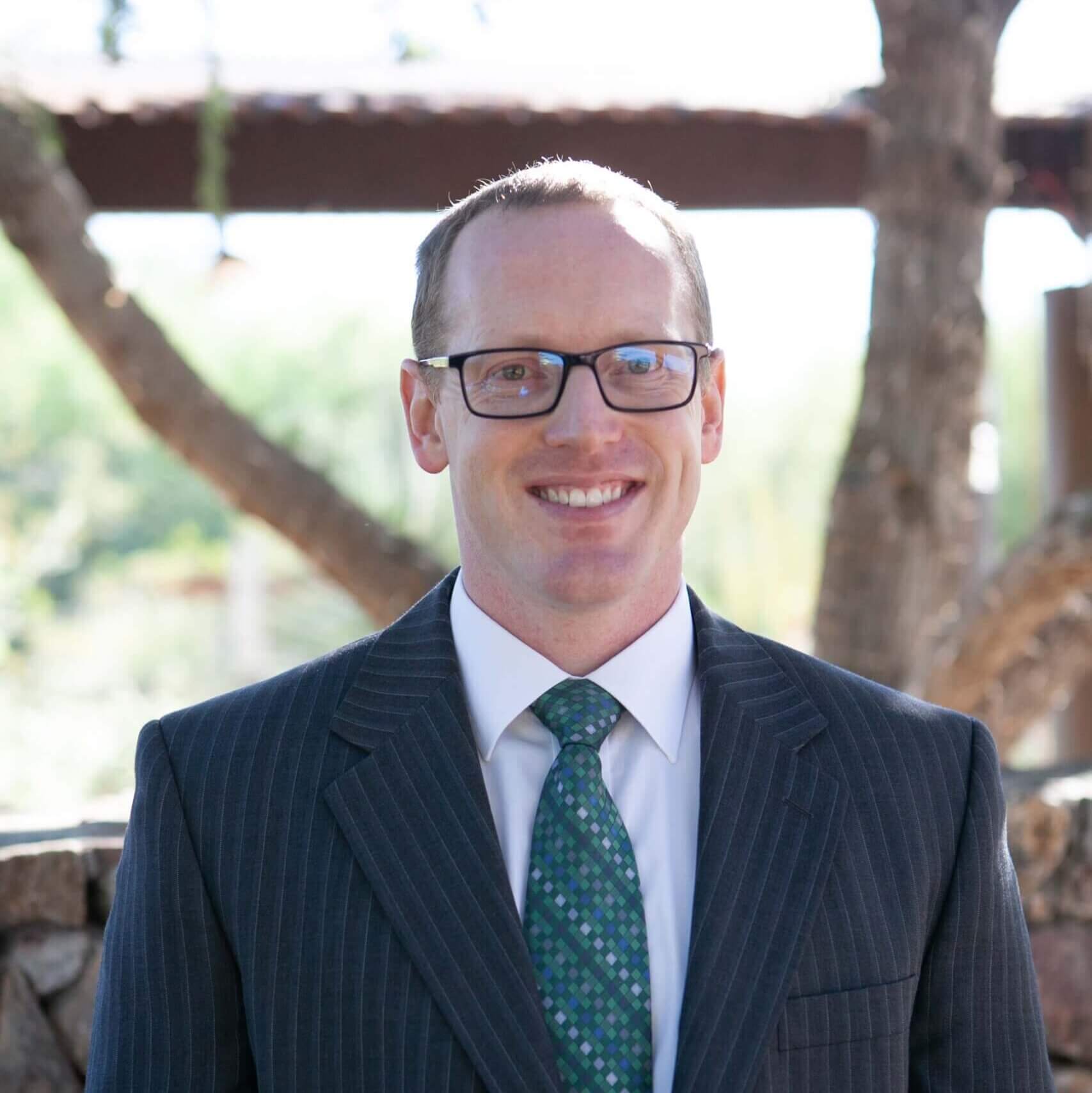 Trevor Rosenlof, a male optometrist with a dark suit and green tie