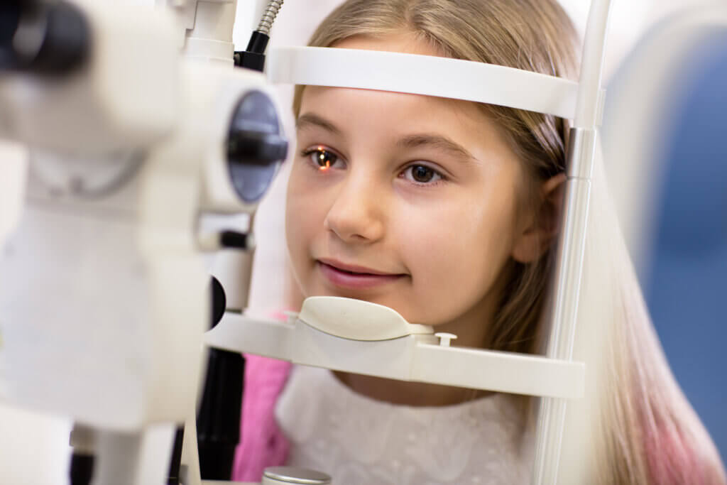 Young girl resting her chin in an eye exam machine during an exam